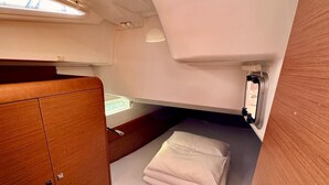 Une petite cabine comprenant un lit, un petit placard et une fenêtre.