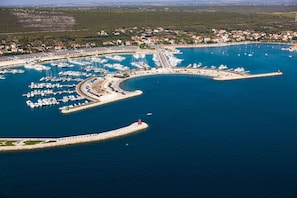 An aerial view of a marina with numerous boats docked, a lighthouse, and a coastal town in the background. - Sun-Kissed Sailing Adventure in Zadar, Croatia (Bibinje)
