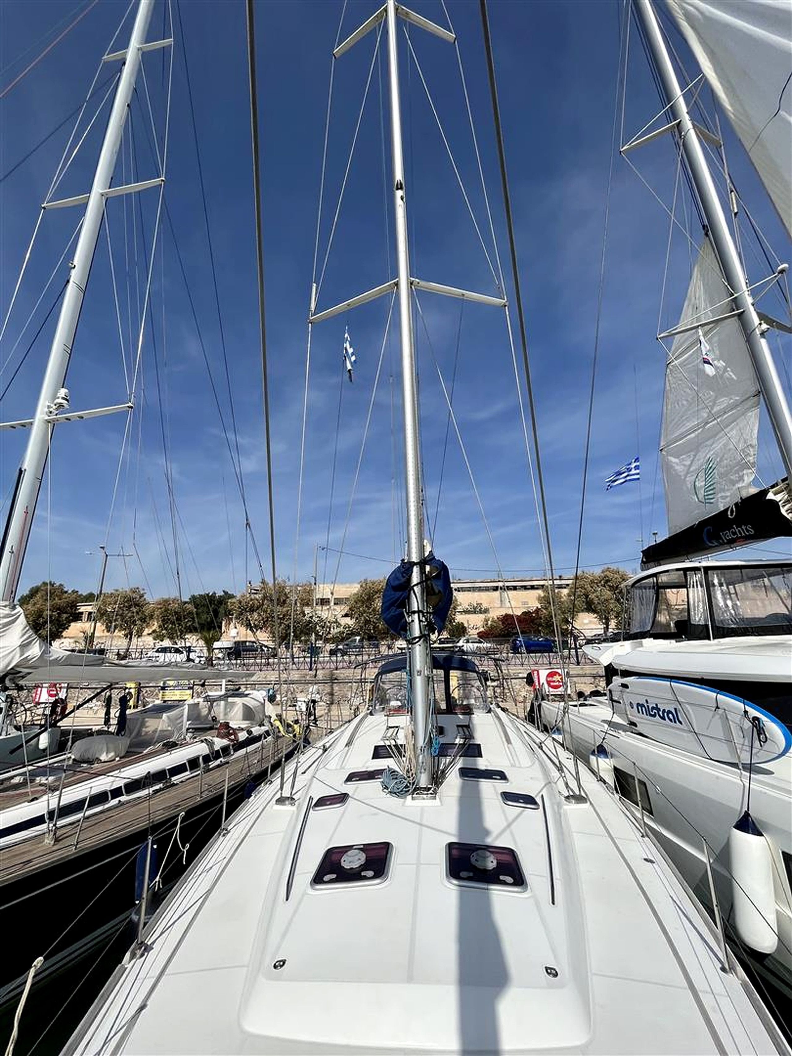 A marina with multiple sailboats docked, featuring masts, rigging, and a clear sky.