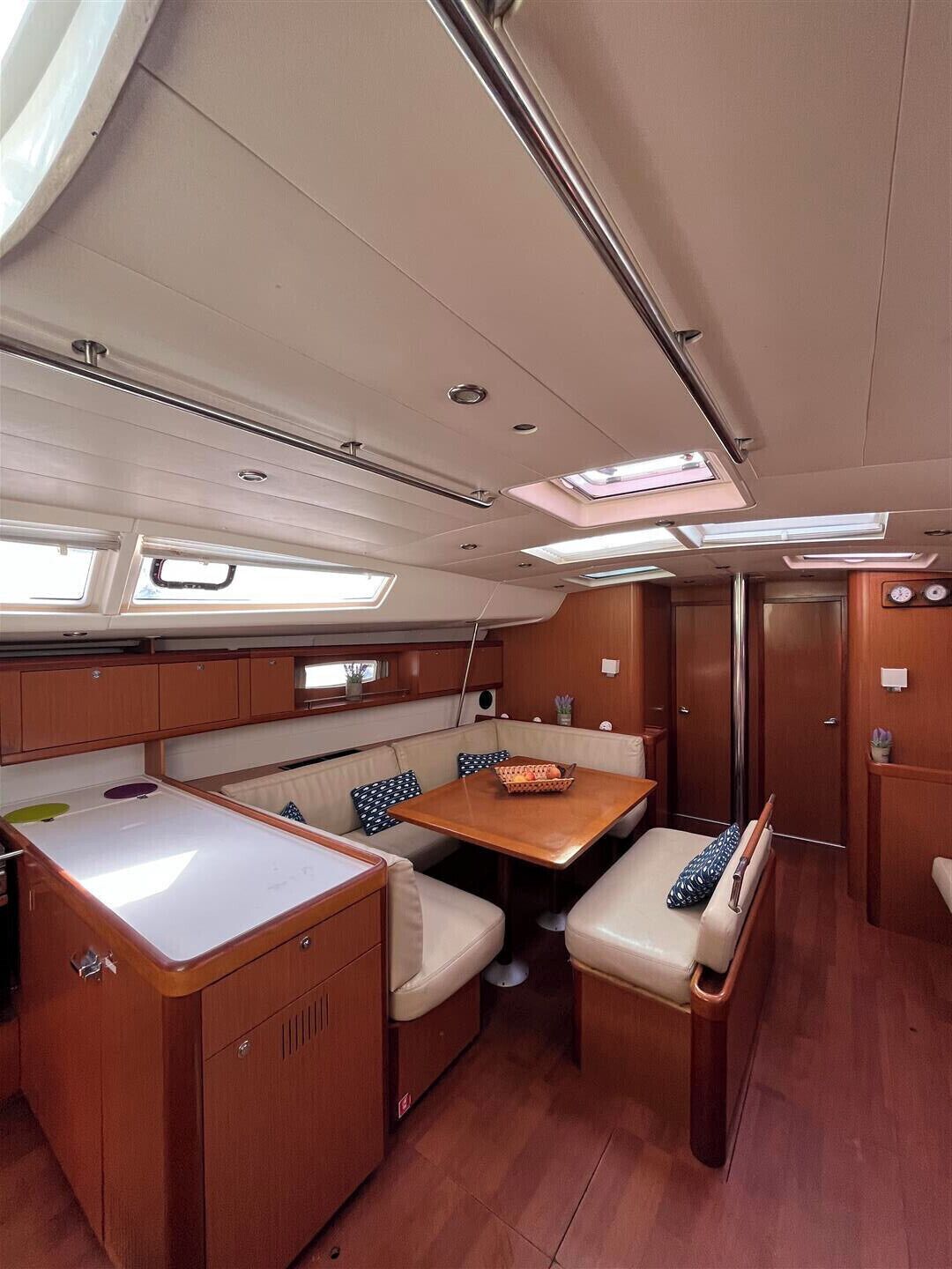 A compact boat interior with a dining area, cushioned seating, and a small kitchen.