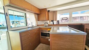 Una cucina compatta con mobili in legno, un lavello in acciaio inossidabile e una finestra vista barche.