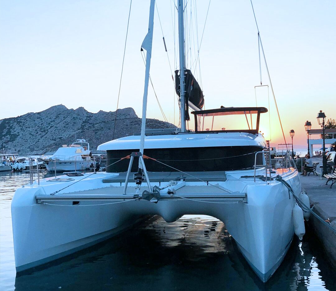 A white yacht docked at a marina with a mountainous backdrop.