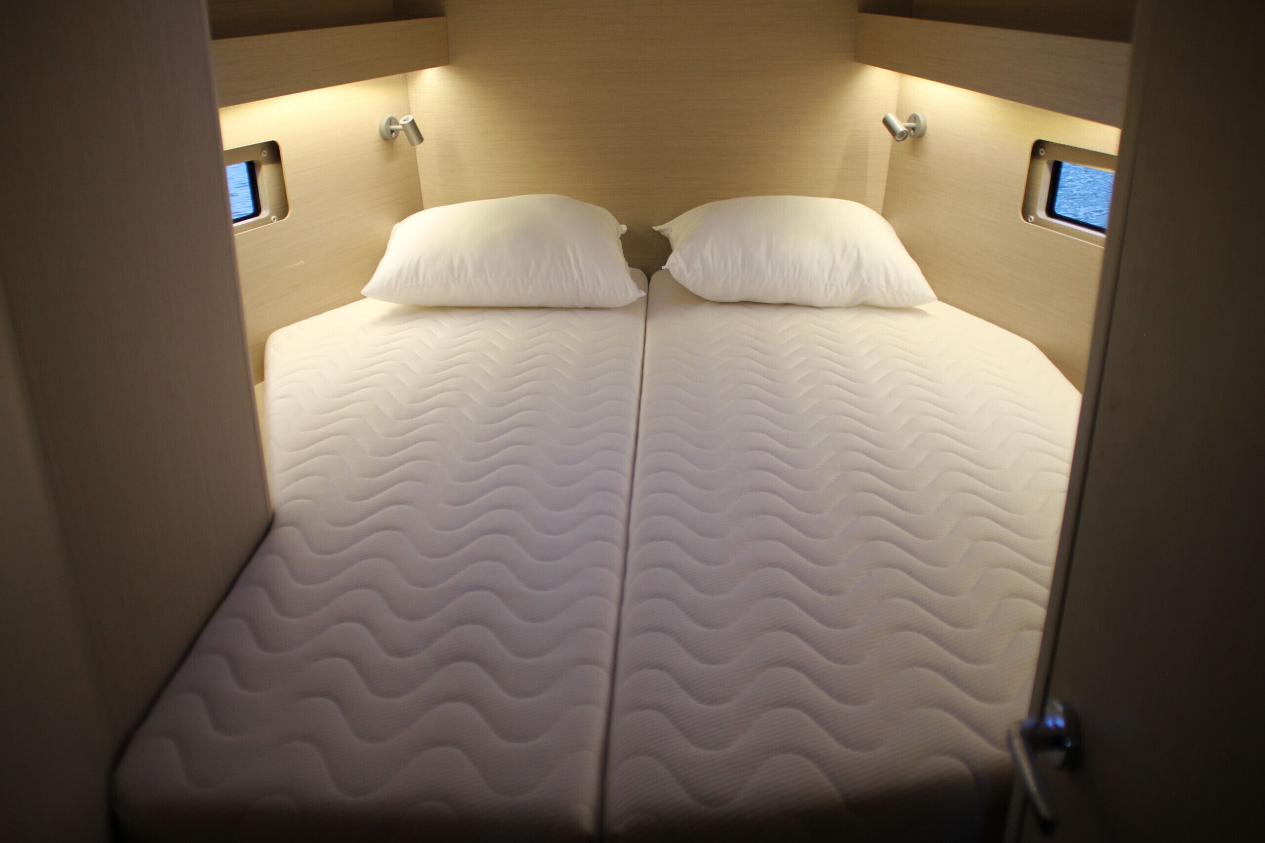 Un lit avec un matelas à motifs ondulés, deux oreillers et une tête de lit dotée d’un éclairage intégré.