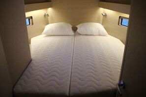 A bed with a wavy mattress pattern, two pillows, and a headboard with built-in lighting. - Sun-Kissed Sailing Adventure in Islas Sarónicas (Piraeus)