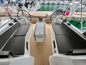 Ein Bootsdeck mit Sitzgelegenheiten, einem Steuer und Blick auf den Hafen.