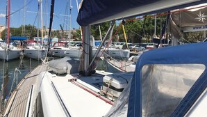 A marina with multiple boats docked, a covered area with a website URL, and a clear sky. - Sun-Kissed Sailing Adventure in Islas Baleares, Mallorca (Palma)
