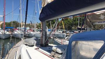 Een jachthaven met verschillende boten afgemeerd, een overdekt gebied met een website-URL, en een heldere lucht.