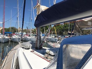 A marina with multiple boats docked, a covered area with a website URL, and a clear sky. - Sun-Kissed Sailing Adventure in Islas Baleares, Mallorca (Palma)