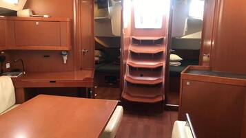 Een compact vakantiehuis met een eettafel, een zithoek en een centraal wandrek met opbergvakken.