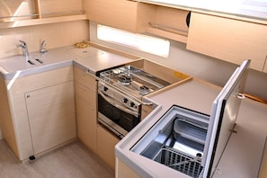 A compact kitchen with a built-in stove, oven, and dishwasher, featuring wooden cabinetry and a countertop. - Sun-Kissed Sailing Adventure in Zadar, Croatia (Zadar)