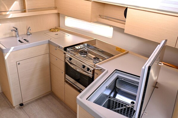 A compact kitchen with a built-in stove, oven, and dishwasher, featuring wooden cabinetry and a countertop. - Sun-Kissed Sailing Adventure in Zadar, Croatia (Zadar)
