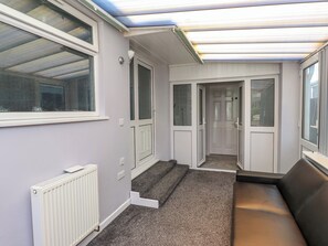 Un couloir avec un radiateur, un banc et une porte donnant sur une autre pièce.