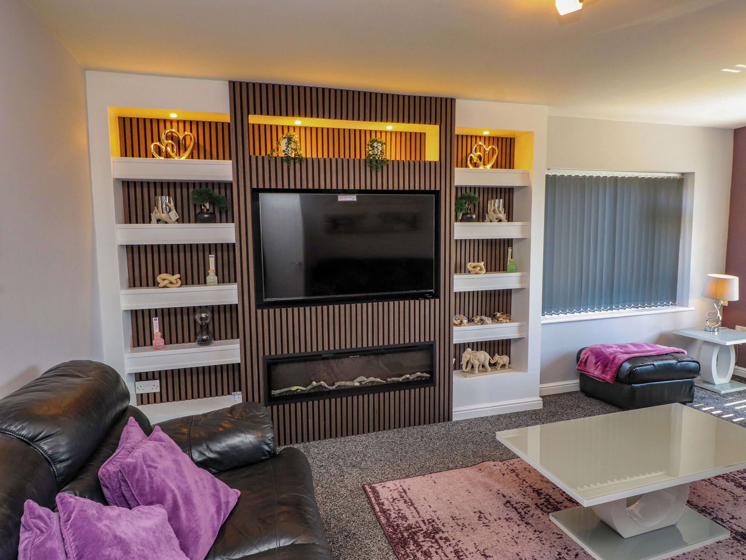 A modern living room with a flat-screen TV, a fireplace, a sofa, and a coffee table.