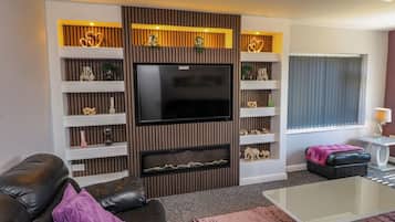 A modern living room with a flat-screen TV, a fireplace, a sofa, and a coffee table.