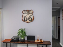 Un escritorio con un cartel de la Ruta 66, una planta en maceta, una computadora portátil y un pequeño florero.