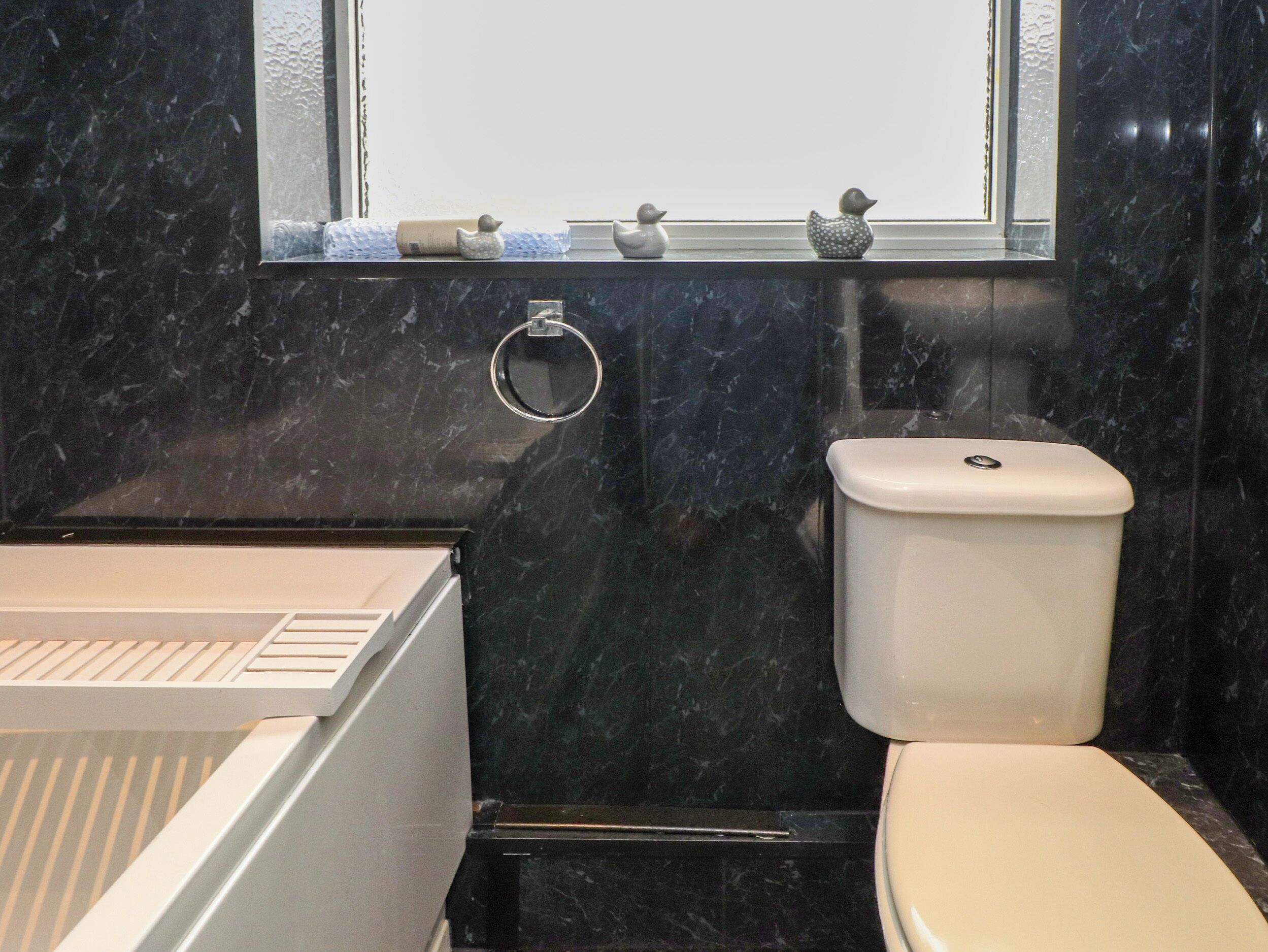 Un baño con inodoro, lavamanos y ventana decorada.