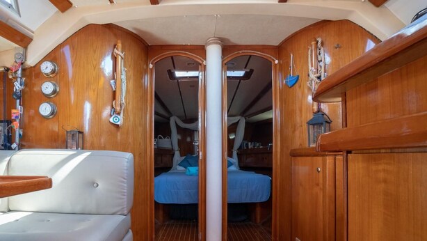 A compact interior with a central column, a bed, a small seating area, and wooden paneling. - Sun-Kissed Sailing Adventure in the Saronic Islands (Palaio Faliro)