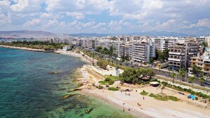 A coastal cityscape with a beach, buildings, and clear water. - Sun-Kissed Sailing Adventure in the Saronic Islands (Palaio Faliro)