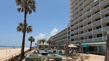 Un hôtel doté d’une piscine, d’un espace extérieur aménagé et de palmiers.