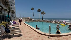 Ein Poolbereich mit Liegestühlen, einem Pool und Blick auf den Strand.
