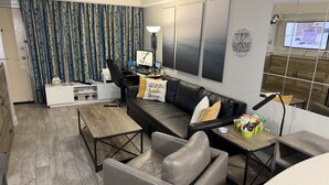 Ein modernes Wohnzimmer mit Sofa, Couchtisch und Schreibtisch mit Computer.