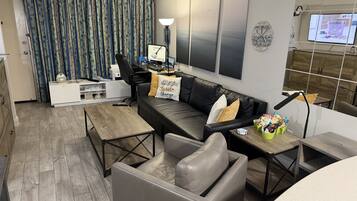 Un salon moderne avec un canapé, une table basse et un bureau avec un ordinateur.