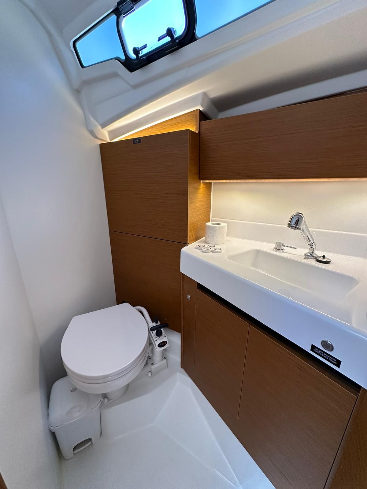Ein kleines Badezimmer mit Toilette, Waschbecken und Fenster.