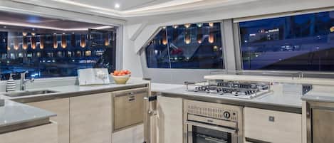 Una cocina moderna con horno integrado, cocina a gas y un amplio ventanal con vistas a un paisaje urbano.