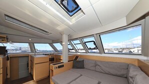 A modern interior with a sofa, a kitchen area, and large windows offering a view of the marina. - Sun-Kissed Sailing Adventure in Istria, Croatia (Pula)
