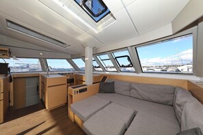 Ein modernes Interieur mit einer Couch, einer Küchenzeile und großen Fenstern mit Blick auf die Marina.