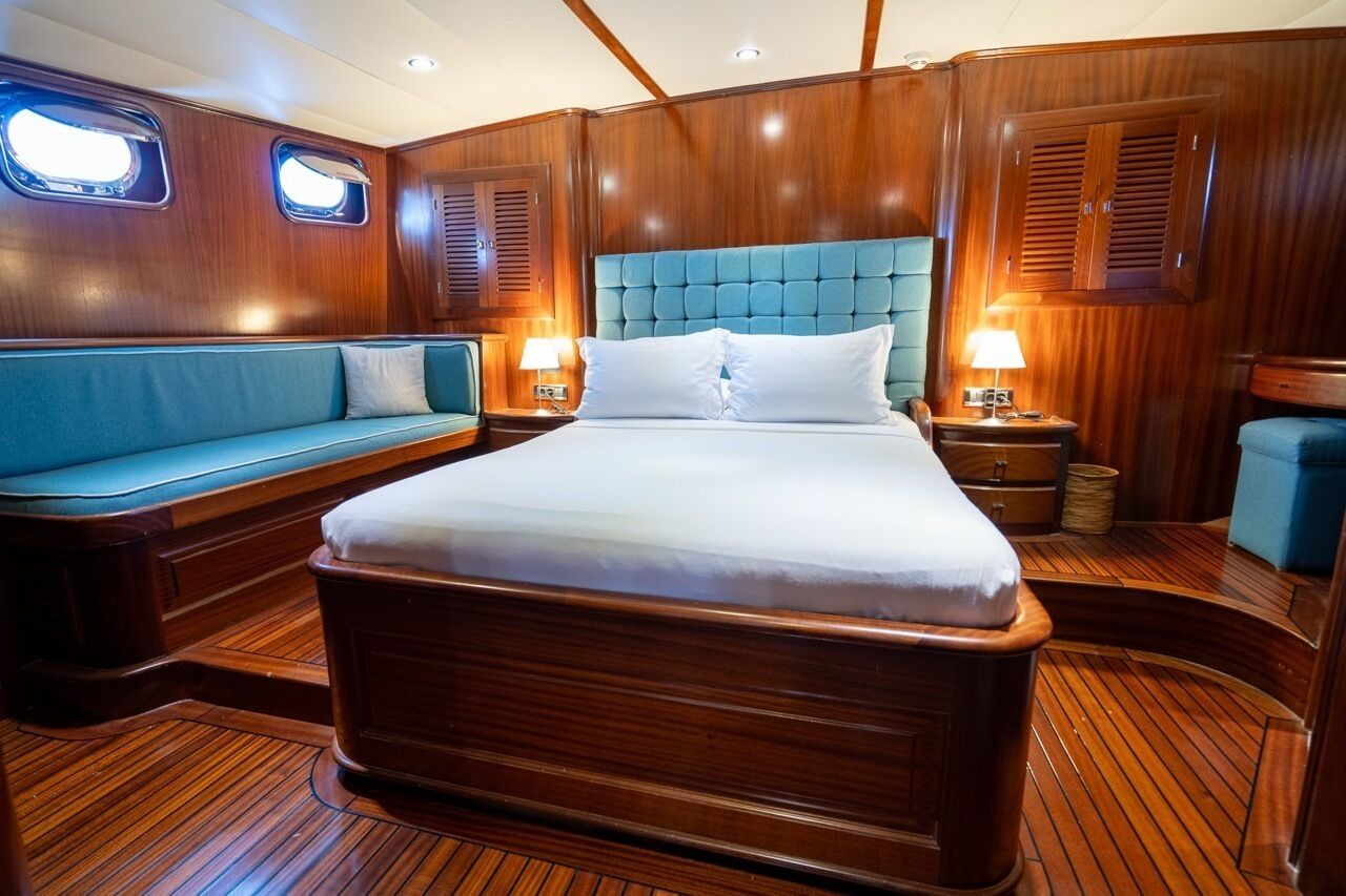Ein Zimmer mit Holzvertäfelung, einem Bett, einer blau gepolsterten Bank und zwei Nachttischlampen.