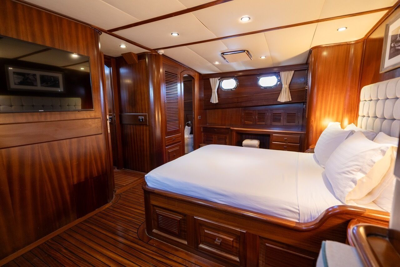 Un dormitorio con paneles de madera, una cama, un tocador y un ventanal.
