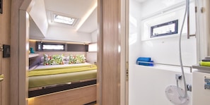 A compact RV interior with a bed, a small kitchenette, and a shower area.