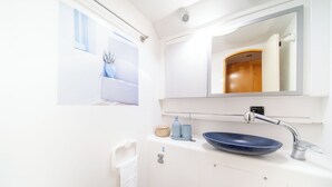 A bathroom with a white sink, a blue bowl sink, a towel rack, and a mirror.