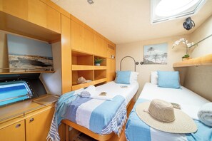 Un dormitorio pequeño con dos camas, un armario de madera, una estantería con una planta y una lámpara de pared.