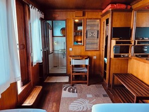 A compact RV interior with wooden walls, a small seating area, and a kitchenette.