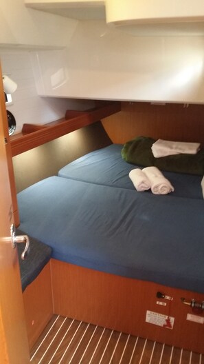 Un lit superposé avec une literie bleue et des serviettes enroulées.