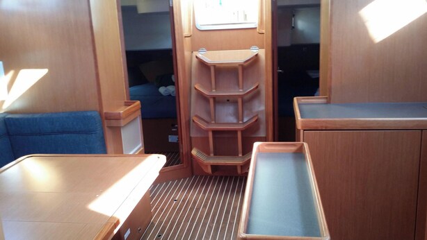 A compact interior with a bed, a blue cushioned seat, and a wooden cabinet with shelves. - Sun-kissed Sailing Adventure in the Ionian Islands (Preveza)