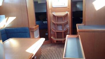 A compact interior with a bed, a blue cushioned seat, and a wooden cabinet with shelves.