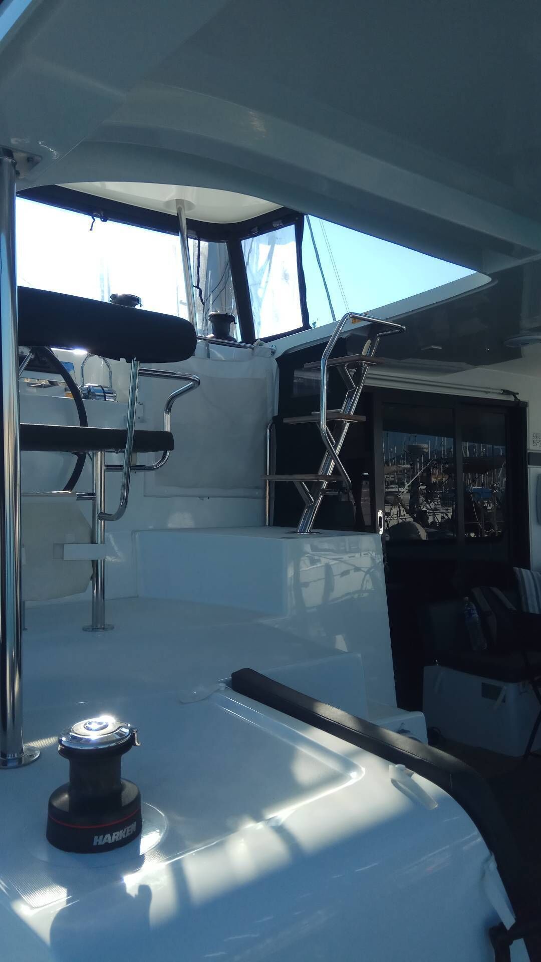 A boat's deck with a winch, a ladder, and a view of the marina.