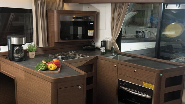 A compact kitchen with a built-in microwave, stove, and oven, a coffee maker, and a small potted plant. - Sun-Kissed Sailing Adventure in the Ionian Islands, Lefkada (Lefkada)