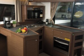 A compact kitchen with a built-in microwave, stove, and oven, a coffee maker, and a small potted plant. - Sun-Kissed Sailing Adventure in the Ionian Islands, Lefkada (Lefkada)