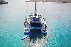 A sailboat with a cabin and deck seating, anchored in clear blue water. - Sun-Kissed Sailing Adventure in Islas Cícladas, Mykonos (Mykonos)