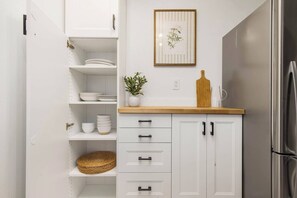 A kitchen with white cabinets, a stainless steel refrigerator, and a framed botanical print on the wall. - Lake City Downstairs 2BR • Movie Nights + Fireplace (Seattle)