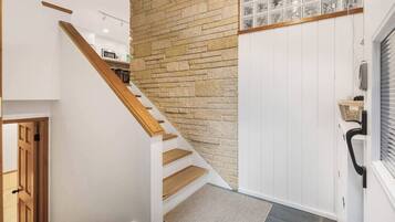 Una escalera de madera que conduce a una habitación con paredes blancas y piso de baldosas.
