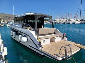 Ein Boot mit überdachtem Sitzbereich, einem Holldeck und einer kleinen Kabine.