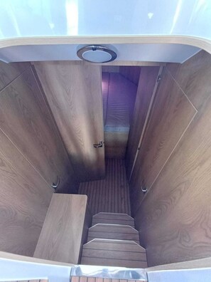A narrow, wooden interior with a staircase leading to a higher level.