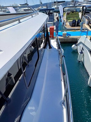 A marina with boats docked, a covered area with seating, and a person standing by the water.