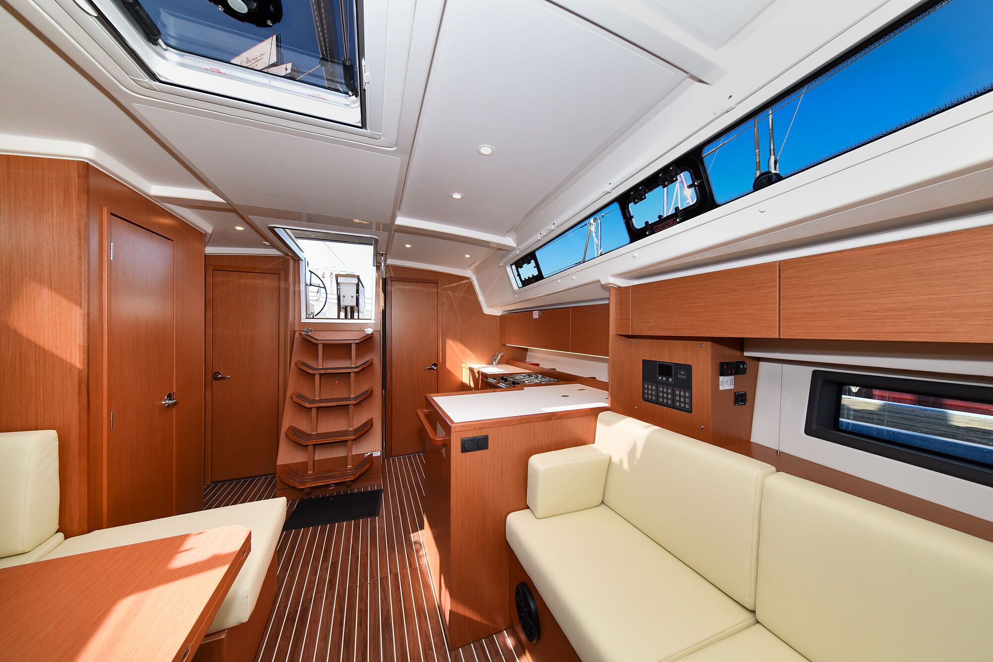 A yacht interior with a dining area, a control panel, and a seating area.