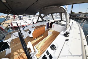 Ein Bootsdeck mit Holzboden, einer Sitzecke und einer Bedienkonsole.